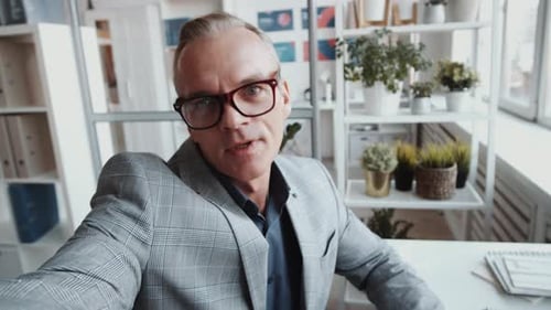 Mid-Aged Businessman Chatting on Online Call in Office