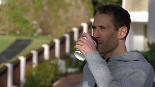 Young caucasian man sitting on a bench drinking coffee in Auckland, New Zealand
