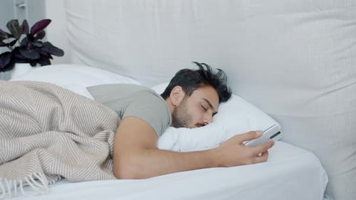 Man Wakes Up and Looks at Cell Phone