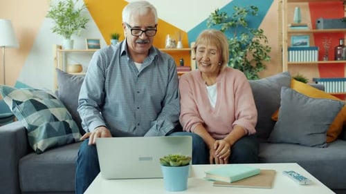 Senior Couple Video Calling on Laptop in Living Room