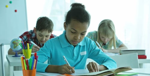 Focused Students Writing at Desks in Classroom