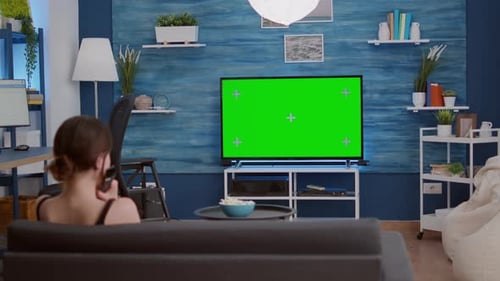 Young Woman Relaxing Televison on Green Screen Mockup Display Changing Stations with Remote Control
