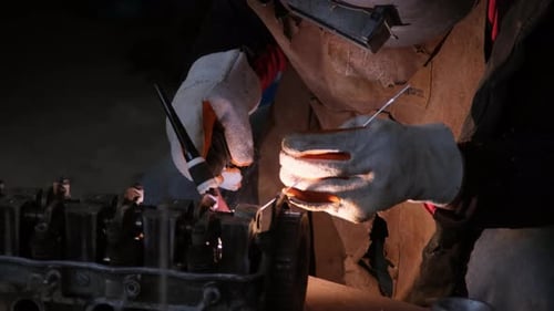 Professional men wearing welding mask and gloves work in home workshop with arc welding and argon.