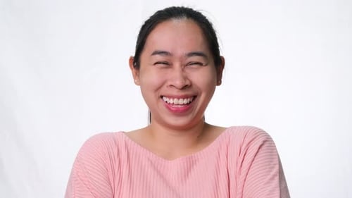 Happy woman laughing and looking at camera on white background in studio
