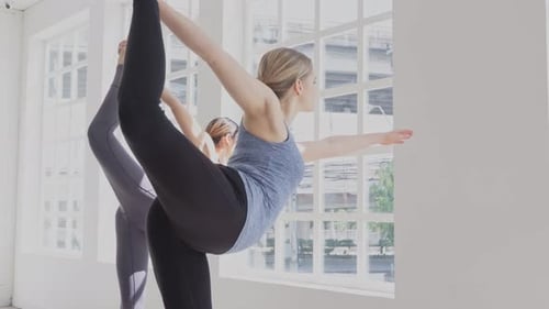 Two woman practicing yoga in fitness studio