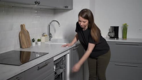 Woman Loading Dishes into Dishwasher in Modern Kitchen