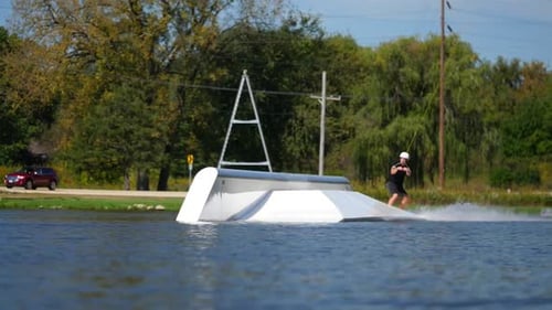 Un hombre monta su tabla de wakeboard en un parque de cables