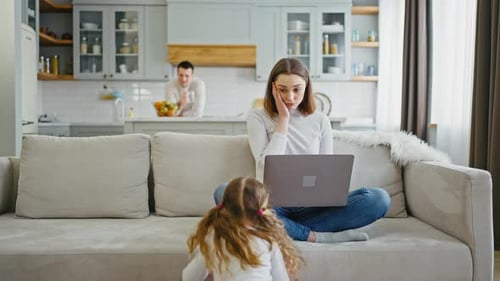 Woman Using Laptop at Home with Child