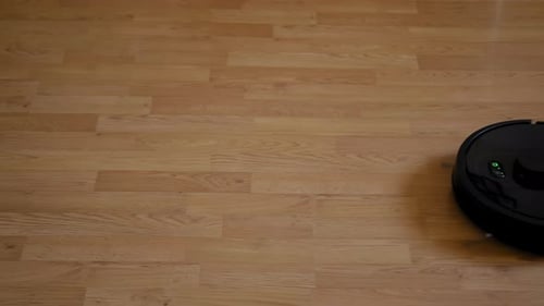 Robot Vacuum Cleaner Moves Across Wood Floor