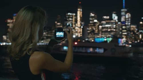 Woman Taking Nighttime Photos of City Skyline