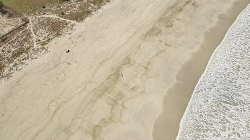 Frau joggt entlang des weißen Sandstrandes mit weißem Schaum vom Strand
