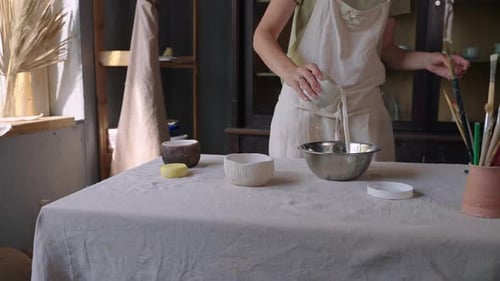 Woman Pouring Milky Liquid into Bowl in Studio