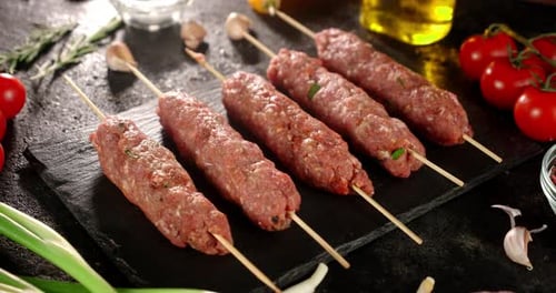 Raw Kebab Sausages on a Stone Board Rotate.