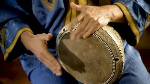 Enge Aufnahme eines Mannes in marokkanischer Kleidung, der arabisches Doumbek, Darbuka oder Derbeki spielt
