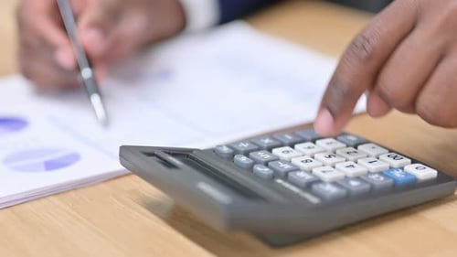 Close-Up of Man Calculating Finances at Desk