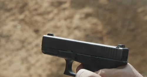 Movimiento lento de una pistola de mano disparando en un campo de tiro con el cartucho volando
