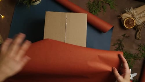 Hands Wrapping a Present With Brown Paper