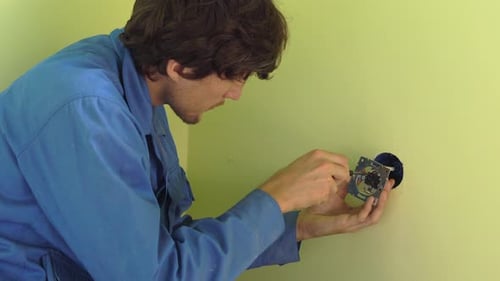 Imagen mediana de un joven electricista profesional reparando enchufes.