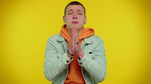 Young Adult Praying Against Yellow Background