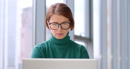 Focused Woman Working on Laptop in Office