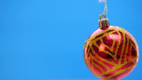 Verzierte rote Weihnachtskugeln drehen sich auf blauem Hintergrund