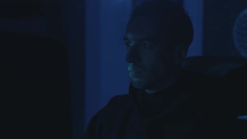 Man Looks at Screen in Dark Home at Night