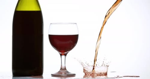 900081 Vinho tinto sendo derramado perto de um copo, contra fundo branco, câmera lenta 4K