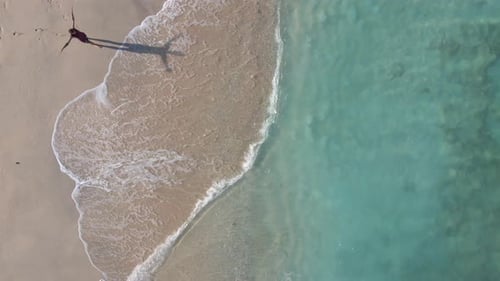 Man with raising arms walking into the clear sea during sunny day on peaceful Gili Island,Asia.