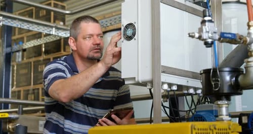 Männlicher Arbeiter nutzt digitales Tablet beim Bedienen der Maschine 4k