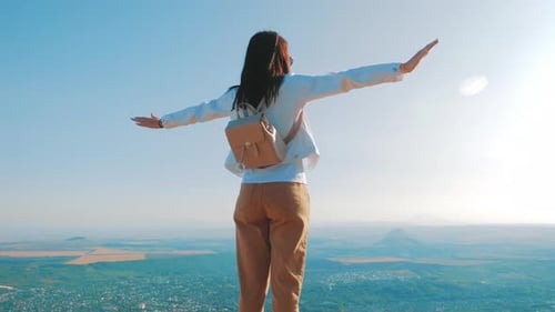 Woman Standing on Mountain Top with Arms Out