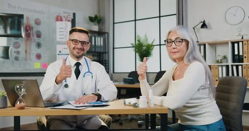 Doctor and His Mature Female Patient Showing Thumbs Up Into Camaera During Her Visit to Clinic