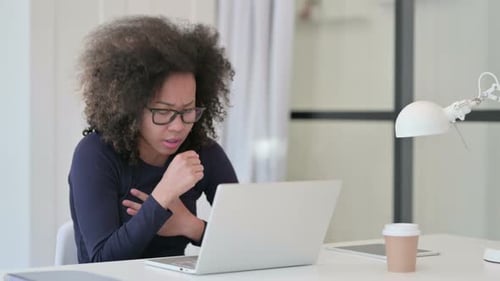 Young Woman Coughing at Laptop in Office