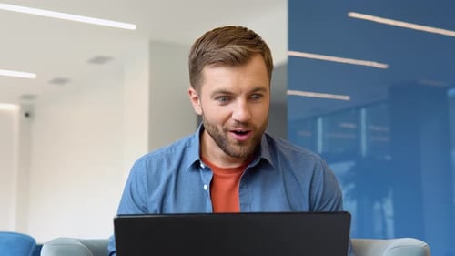 Excited Man Cheers at Laptop in Modern Office