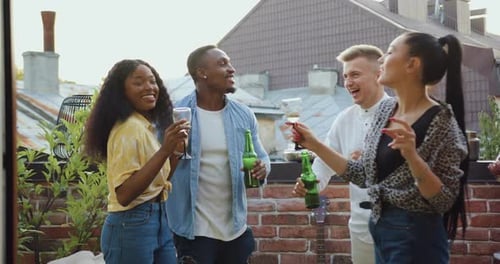 Friends Celebrate Together on Urban Rooftop with Drinks