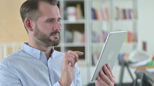 Man Celebrates Good News on Tablet Indoors