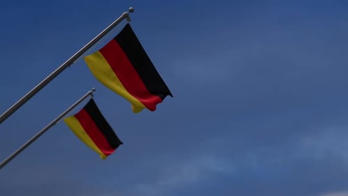 Two Realistic German Flags Waving Against Blue Sky