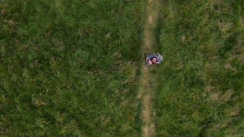 Aerial of a Man Walks Along the Pathway Through Green Meadow