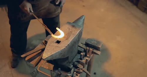 Blacksmith Shaping Glowing Metal on Anvil