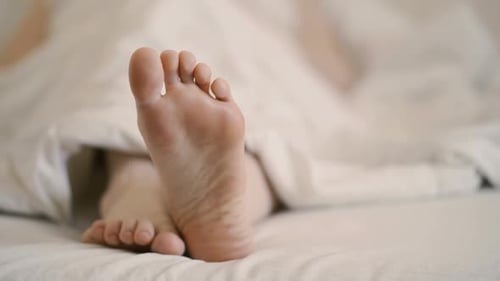 Foot Wiggling Under White Comforter Close Up