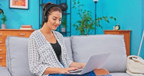 Woman Typing on Laptop with Headphones at Home