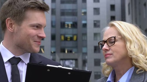 Young Adult Showing Documents to Mature Adult Outdoors