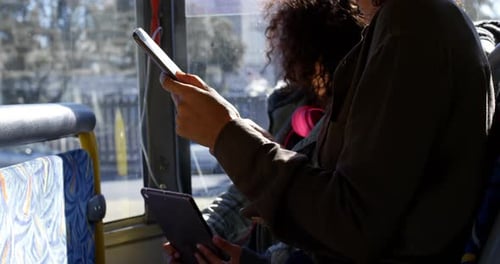Young Adults Ride Bus Using Phone and Tablet