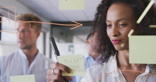 Professional businesswoman sticking memo notes on glass-board in modern office in slow motion