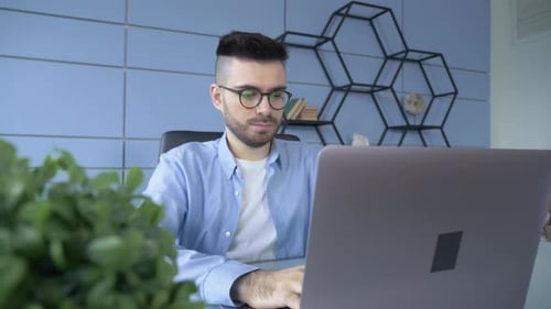 Professional Creative Man Sitting at His Desk in Home Office Studio Working on a Laptop