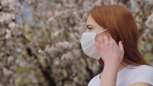 Pretty Female Taking Off Face Mask in Blooming Park