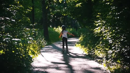 A Girl in Helmet Skating in the Forest on Her Rollers