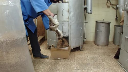 Worker Uses Tool to Transfer Grain in Factory