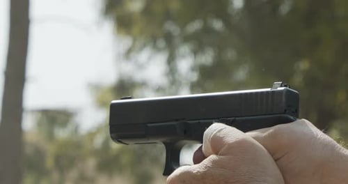 Zeitlupe eines Mannes, der eine Handfeuerwaffe auf einem Schießstand mit wegfliegender Patrone ab