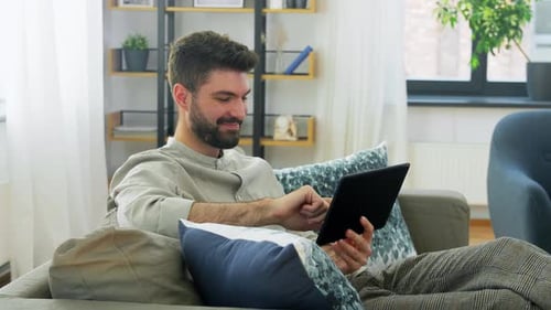 Man Using Tablet on Couch at Home