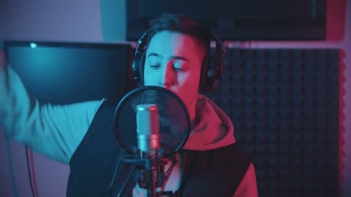 A Man in Hoodie Rapping in the Sound Recording Studio